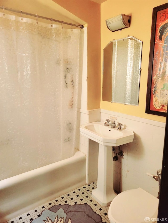 bathroom featuring shower / bathtub combination with curtain, toilet, wainscoting, and tile patterned flooring