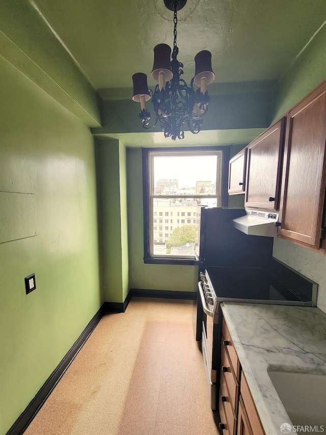 kitchen with light floors, baseboards, a chandelier, and electric range oven