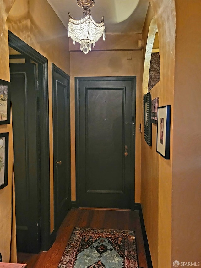 doorway to outside with dark wood-type flooring and a notable chandelier