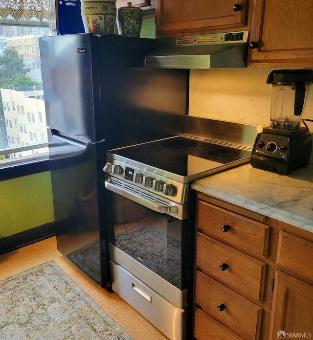 kitchen featuring under cabinet range hood, stainless steel electric stove, brown cabinets, and light countertops