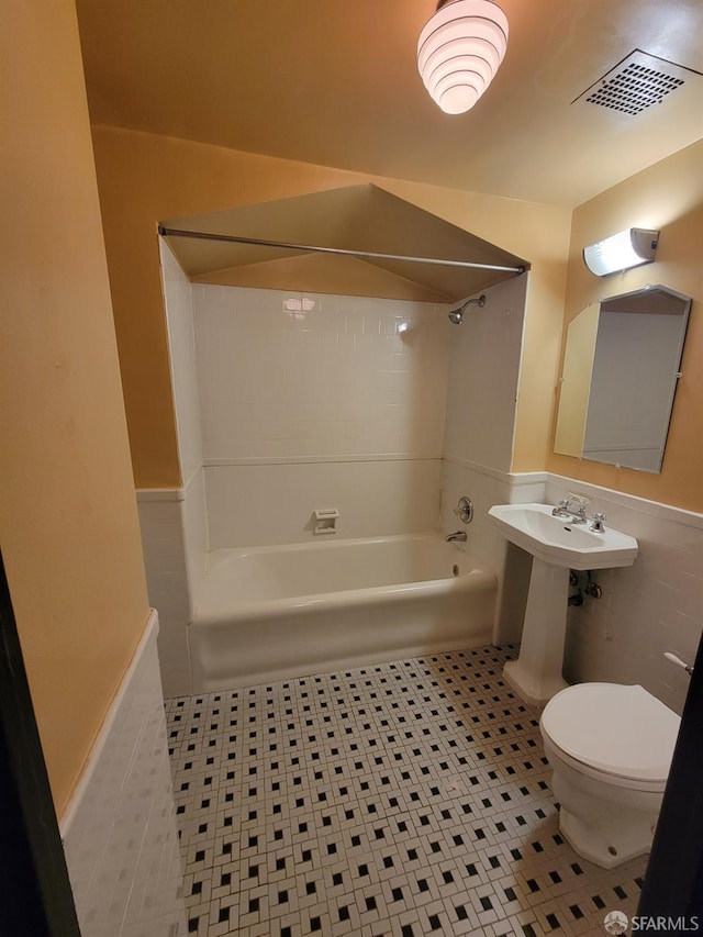 full bathroom with toilet, washtub / shower combination, visible vents, and wainscoting