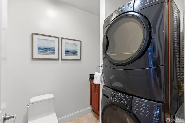 washroom featuring stacked washing maching and dryer, laundry area, and baseboards