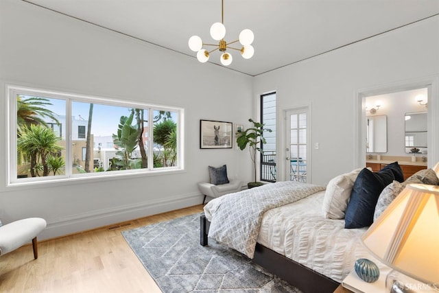 bedroom with a chandelier, connected bathroom, wood finished floors, visible vents, and baseboards