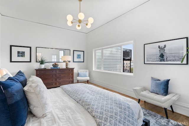 bedroom featuring a notable chandelier, baseboards, and wood finished floors