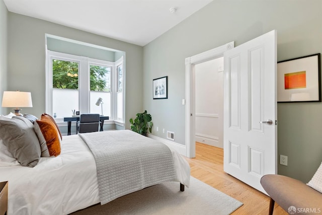 bedroom with baseboards, visible vents, and light wood finished floors