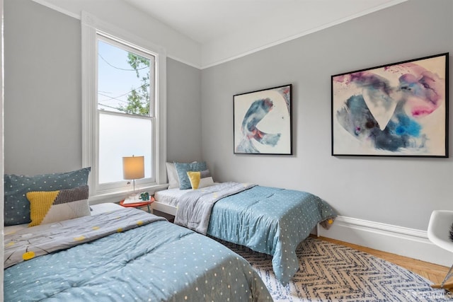 bedroom with multiple windows, baseboards, and wood finished floors