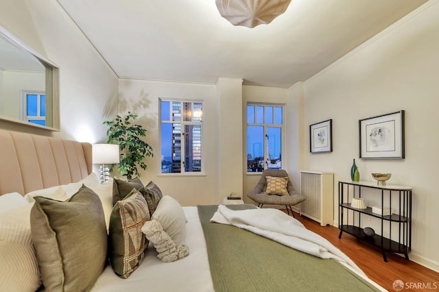 bedroom with ornamental molding, wood finished floors, and baseboards