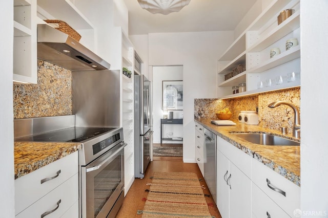 kitchen featuring appliances with stainless steel finishes, wall chimney range hood, white cabinetry, open shelves, and a sink