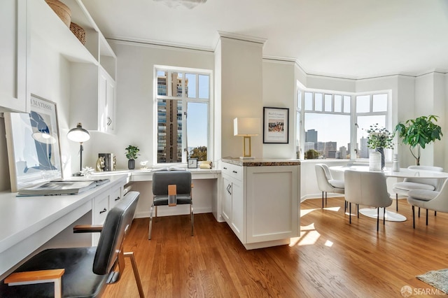 kitchen with a peninsula, crown molding, white cabinets, and wood finished floors