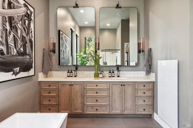 bathroom featuring tile patterned flooring, a soaking tub, a sink, and double vanity