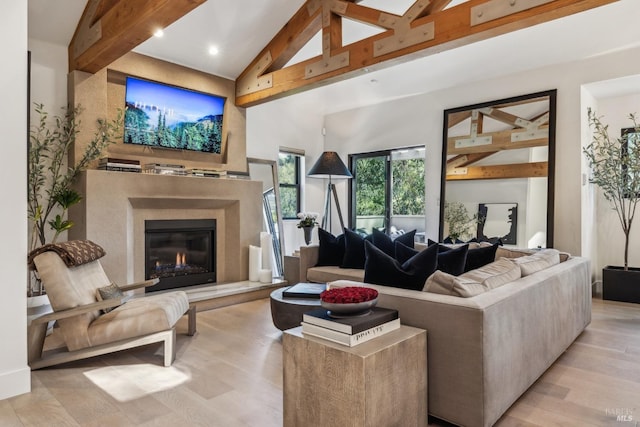 living area with a premium fireplace, light wood-style flooring, beam ceiling, and high vaulted ceiling
