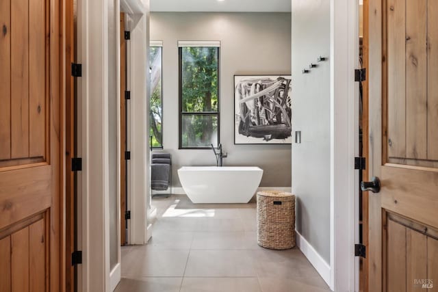 bathroom featuring a freestanding tub, tile patterned floors, and baseboards