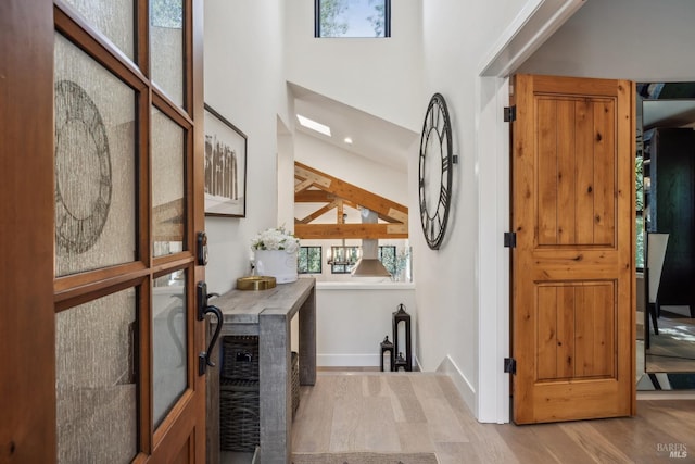foyer entrance with wood finished floors, a high ceiling, and baseboards