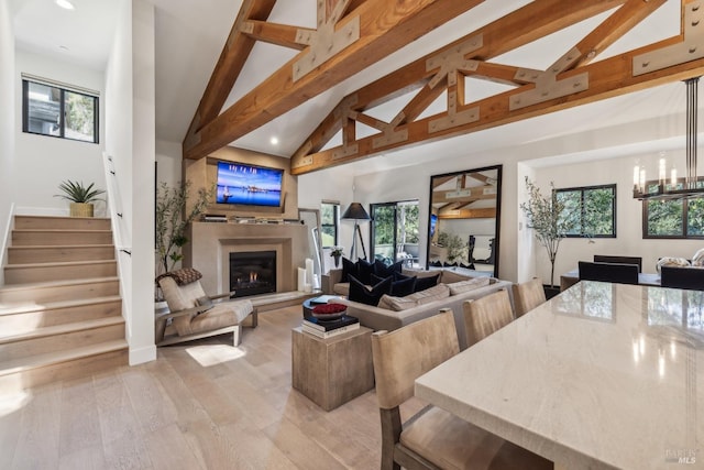 living room featuring light wood finished floors, a warm lit fireplace, stairs, and recessed lighting