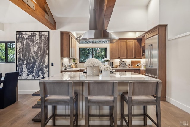 kitchen with baseboards, island exhaust hood, and tasteful backsplash