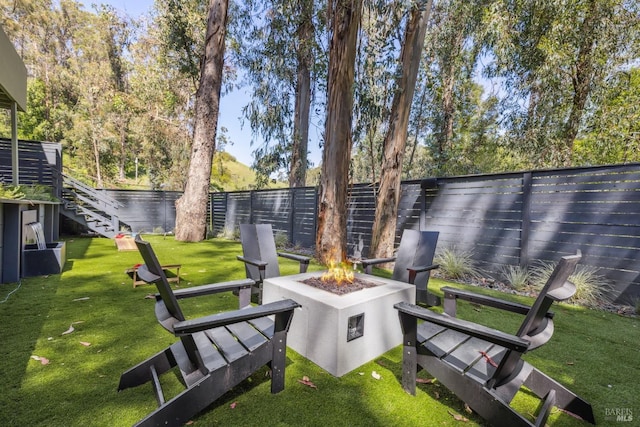 view of yard featuring a fenced backyard, a fire pit, and a water view