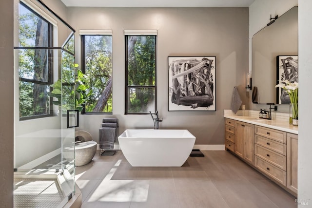 bathroom with a soaking tub, baseboards, vanity, and tile patterned floors