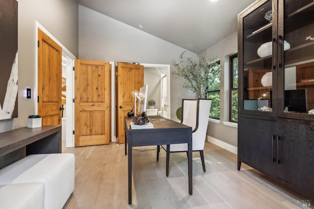 office area featuring light wood finished floors, vaulted ceiling, and baseboards