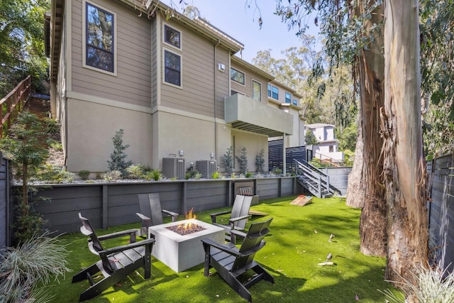 rear view of property with a fire pit, a yard, and stucco siding