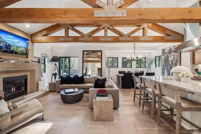 living area featuring beam ceiling, a wealth of natural light, a chandelier, and a high end fireplace