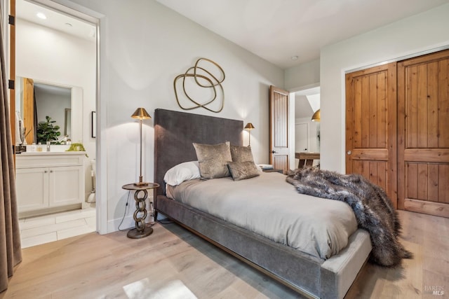bedroom with light wood-style floors, a closet, and connected bathroom