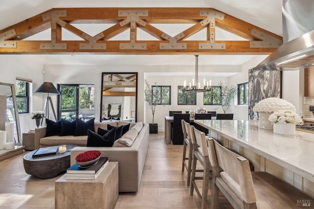 living area featuring light wood finished floors, vaulted ceiling with beams, and an inviting chandelier