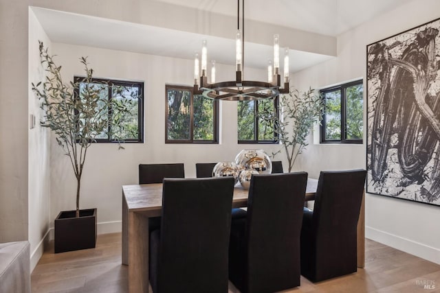 dining area featuring baseboards, wood finished floors, and a chandelier