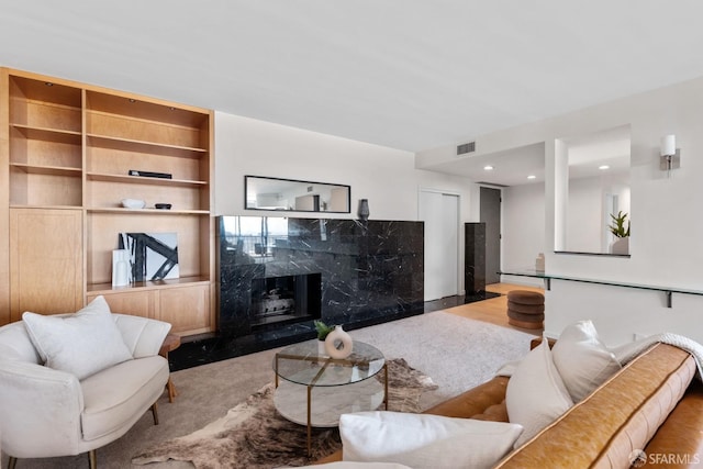 living room with a high end fireplace, visible vents, and recessed lighting