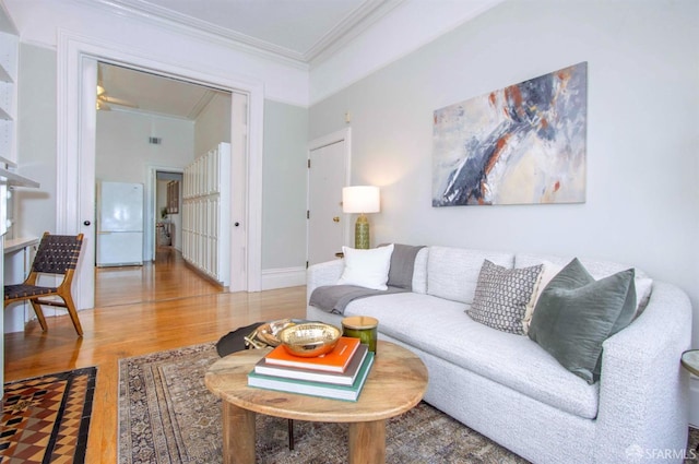 living room featuring baseboards, ornamental molding, and wood finished floors