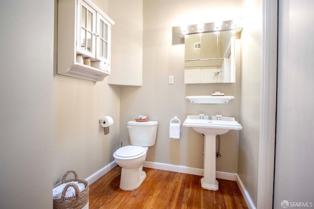 half bathroom with a sink, wood finished floors, toilet, and baseboards