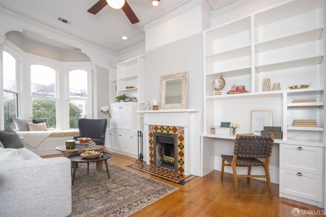 living area with built in features, a fireplace, visible vents, light wood-style floors, and built in study area