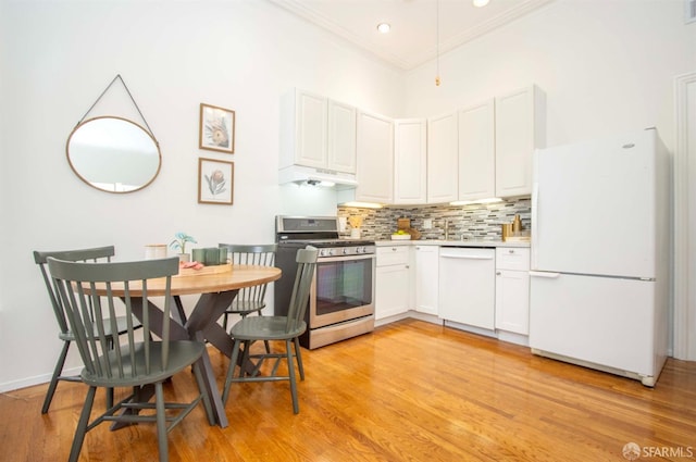 kitchen with under cabinet range hood, white appliances, white cabinetry, light countertops, and tasteful backsplash