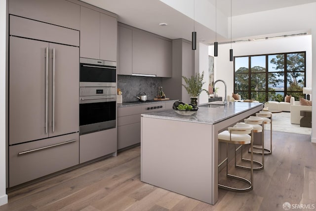 kitchen with double oven, gray cabinets, paneled fridge, and light hardwood / wood-style floors