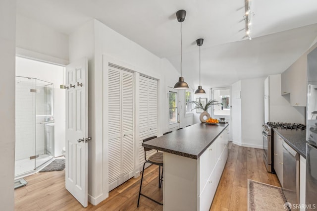 411 Clipper St, San Francisco, CA 94114 - kitchen with dark countertops, stainless steel appliances, a kitchen breakfast bar, light wood-style floors, and a kitchen island