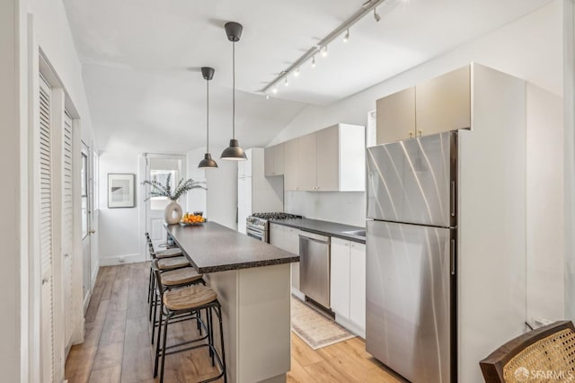 411 Clipper St, San Francisco, CA 94114 - kitchen featuring appliances with stainless steel finishes, dark countertops, a center island, light wood-type flooring, and track lighting