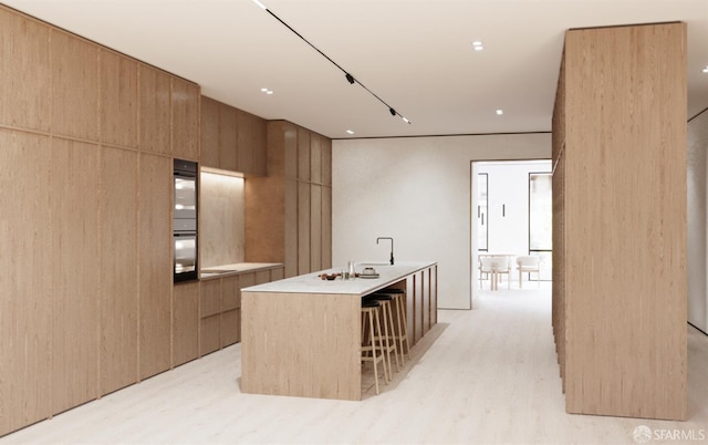 411 Clipper St, San Francisco, CA 94114 - kitchen featuring modern cabinets, a kitchen island with sink, light wood-style floors, and light countertops