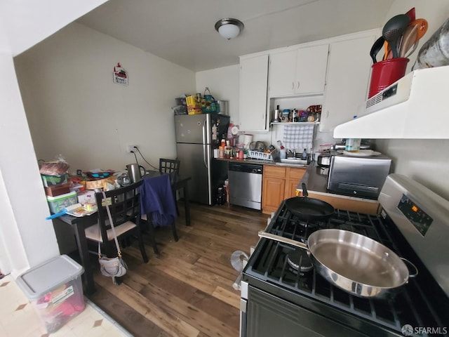 kitchen with appliances with stainless steel finishes, white cabinetry, dark wood-type flooring, and sink