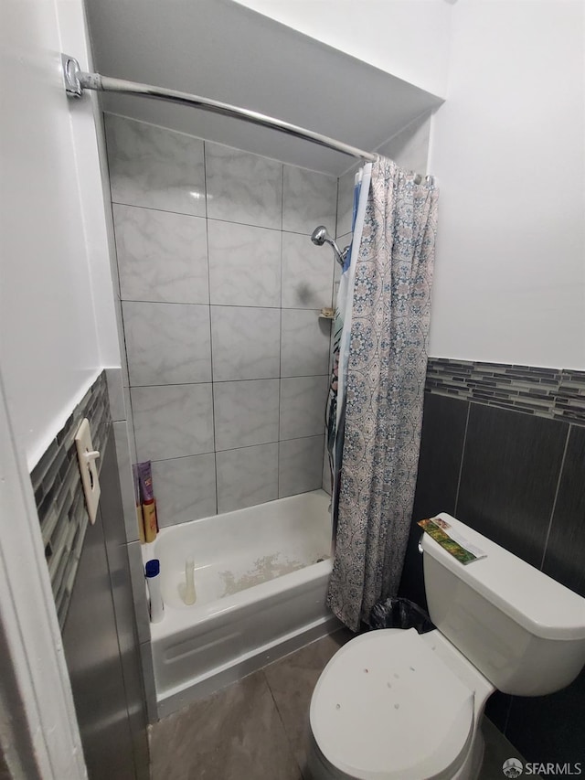 bathroom featuring tile patterned flooring, curtained shower, toilet, and tile walls