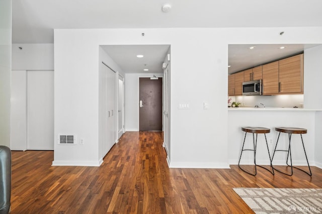 555 4th St Unit 636, San Francisco, CA 94107 - kitchen featuring stainless steel microwave, dark wood-style floors, a breakfast bar, light countertops, and recessed lighting