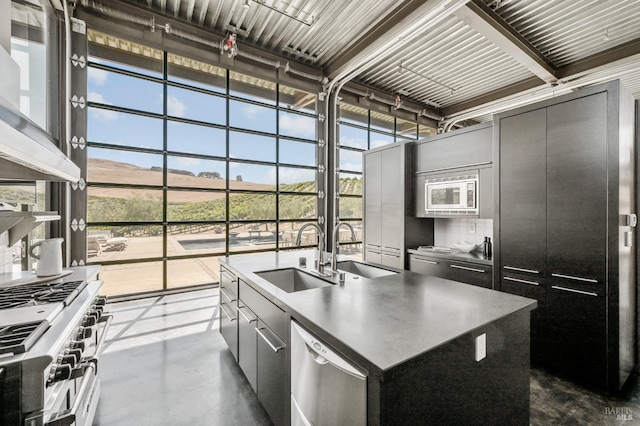 kitchen with finished concrete floors, an island with sink, a sink, and stainless steel appliances