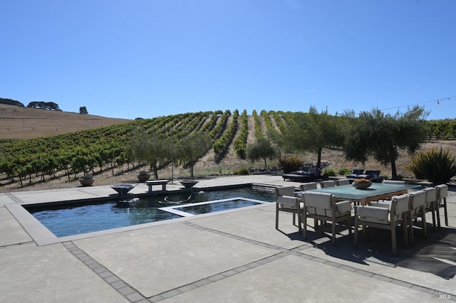 view of pool featuring a rural view, a jacuzzi, outdoor dining space, and a patio area