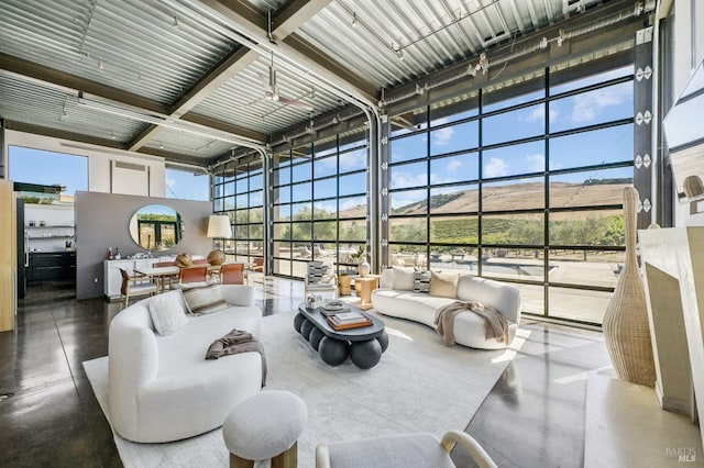 living area featuring a sunroom, a high ceiling, concrete flooring, and floor to ceiling windows