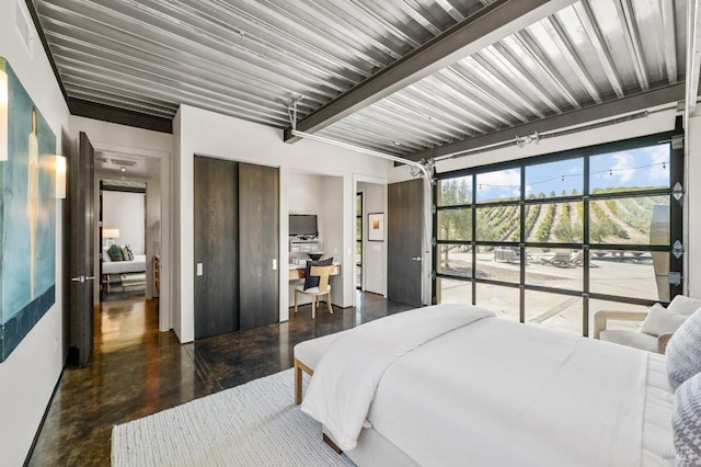 bedroom with finished concrete flooring and beam ceiling