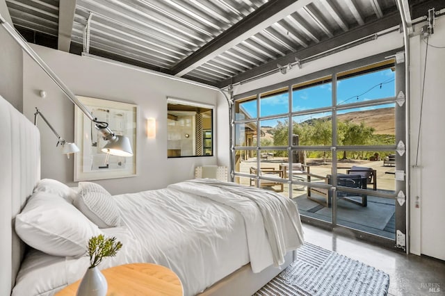 bedroom featuring concrete floors, beamed ceiling, and access to outside