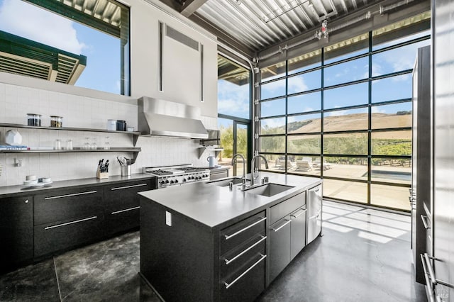 kitchen with wall chimney range hood, a sink, and dark cabinetry
