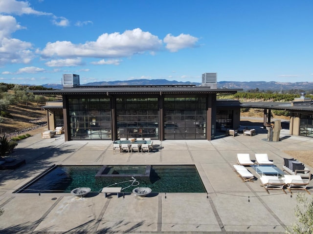 exterior space featuring a mountain view and a pool with connected hot tub