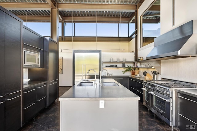 kitchen with concrete floors, built in appliances, wall chimney exhaust hood, and a sink