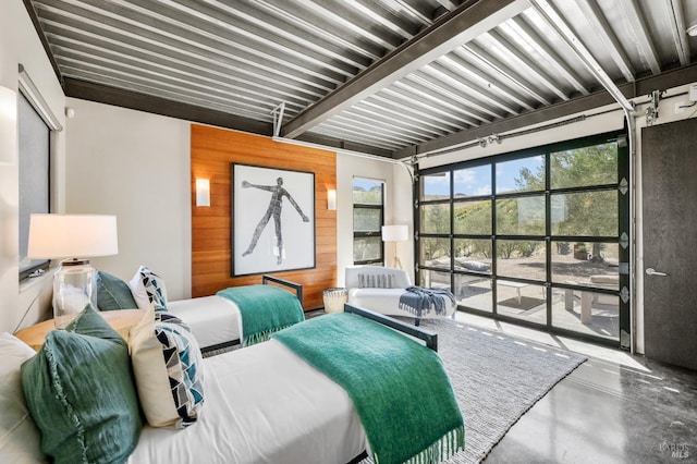 bedroom featuring concrete flooring, wood walls, and a garage