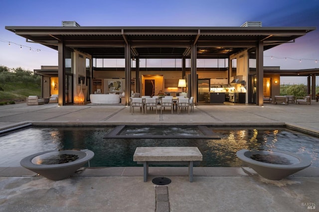 back of property with a patio area, an outdoor living space, a pool with connected hot tub, and a chimney