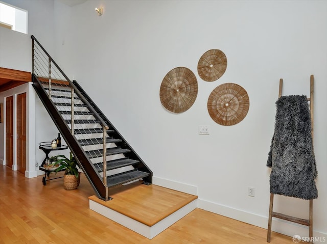 stairway with a high ceiling and hardwood / wood-style flooring